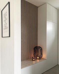 candles are lit in front of a white wall with vertical slatted panels on it