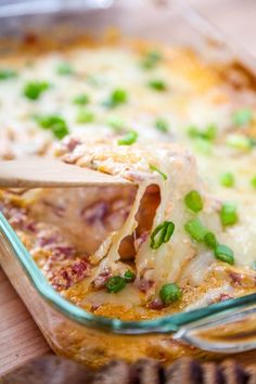 a glass casserole dish filled with lasagna and cheese, topped with green onions