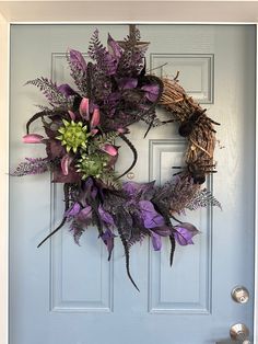 a wreath with purple flowers and greenery hangs on the front door's blue door