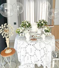 a table topped with lots of white flowers and balloons