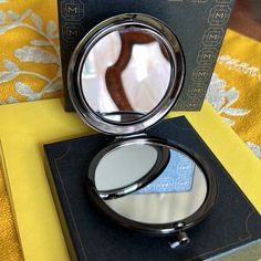 a compact mirror sitting on top of a table next to a yellow and black box