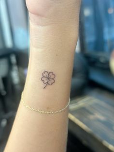 a woman's wrist with a four leaf clover tattoo on the left side of her arm