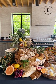 an assortment of breads, fruits and other foods on a table in a kitchen