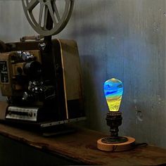 a small lamp sitting on top of a wooden table next to an old fashioned camera