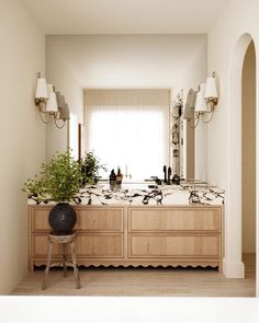 a bathroom with two sinks, mirrors and a potted plant on top of the counter