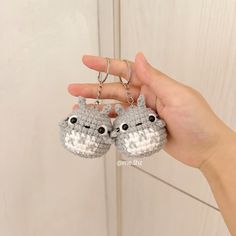 a hand holding two tiny crocheted keychains in front of a door