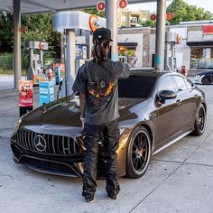 a person standing next to a car at a gas station