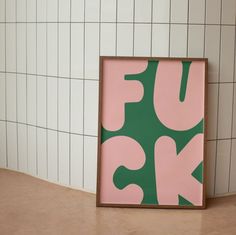 a pink and green print on a white tiled wall next to a brown framed object