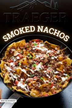 a skillet filled with nachos sitting on top of a table next to a sign that says smoked nachos