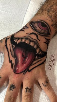 a man's hand with tattoos on it and an evil face painted on the palm