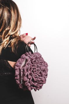 a woman is holding a crocheted purse