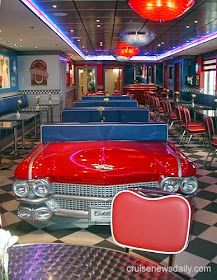 an old red car is parked in a restaurant with tables and chairs on the floor