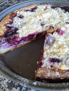 a blueberry crumb cake is cut into slices on a metal platter with one slice missing