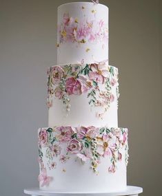 a three tiered white cake with pink flowers on it