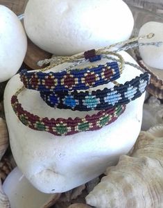 three bracelets sitting on top of a white rock next to shells and seashells