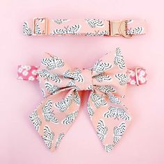 a pink and white bow tie on top of a pink wall next to a pair of clips