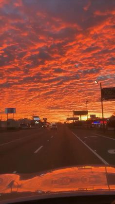 the sun is setting over an empty highway with cars driving down it and street signs in the distance