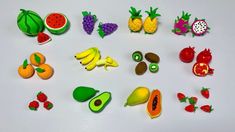 various fruits and vegetables are arranged on a white surface, including bananas, kiwis, oranges, watermelon, avocados