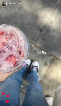 a person is holding a drink with ice and strawberries in the cup on their left hand