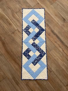 a blue and white quilted table runner sitting on top of a hard wood floor