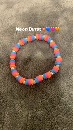 the neon colored beaded bracelet is laying on top of a gray blanket with hearts