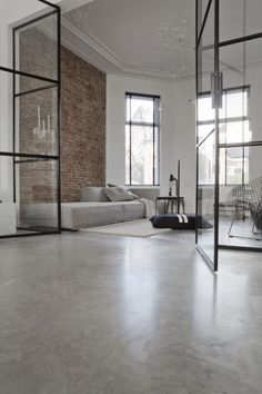 an empty living room with large windows and brick wall