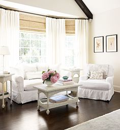 a living room filled with white furniture and flowers in vases on the coffee table