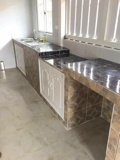 an empty kitchen with marble counter tops and white cabinets in the middle of the room