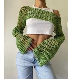 a woman wearing a green knitted top and jeans with her hands on her hips