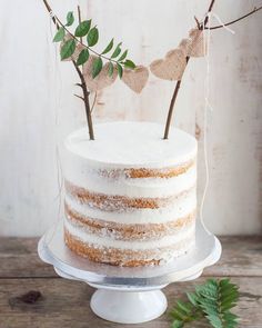 a white cake with frosting and two small leaves on top, sitting on a plate