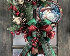 a christmas wreath hanging on the front door with santa claus and pine cones in it