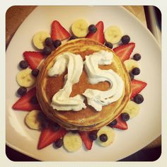 pancakes with whipped cream and fruit arranged in the shape of the number 25 on top