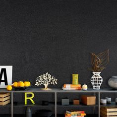 a shelf with books, vases and other decorative items on it in front of a black wall