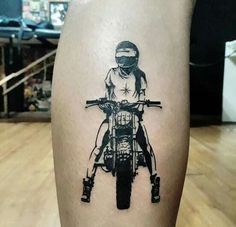 a person on a motorcycle with a helmet and goggles tattooed on their leg, sitting on a wooden floor