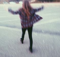 a blurry photo of a woman walking down the street with her arms spread out