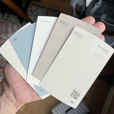 a person holding four different shades of paint in their hand, one is white and the other is blue