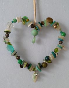 a heart made out of beads and other items hanging from a string on a wall