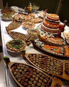 a table topped with lots of different types of sushi and other foods on wooden paddles