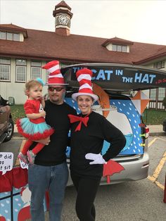 a man and woman standing next to a van with cat in the hat on it