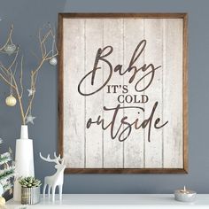 a wooden sign that says baby it's cold outside next to some christmas decorations