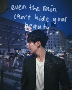 a man standing in front of a city street at night with the words even the rain can't hide your beauty