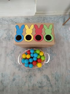 a wooden box filled with colorful candies next to a bowl of chocolate easter eggs