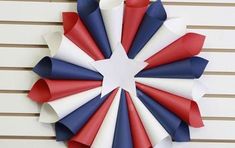 a red, white and blue paper wreath hanging on the side of a building