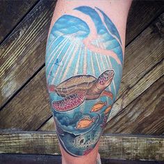 a man's leg with a turtle and fish tattoo on it