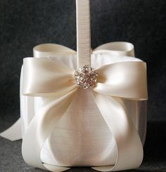 a close up of a white ribbon with a bow on it's side and a diamond brooch in the center