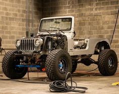 a jeep is being worked on by a man with a hose in front of it