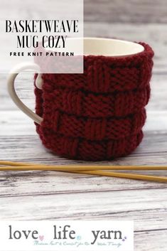 a knitted mug cozy sitting on top of a wooden table next to two knitting needles