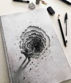 a spiral notebook with pencils and crayons next to it