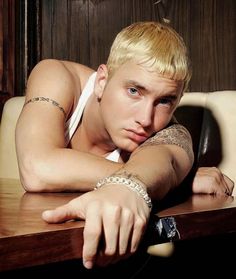 a young man with blonde hair leaning on a table