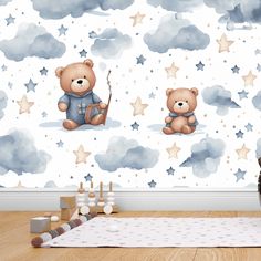 a teddy bear sitting on the floor in front of a wall with stars and clouds